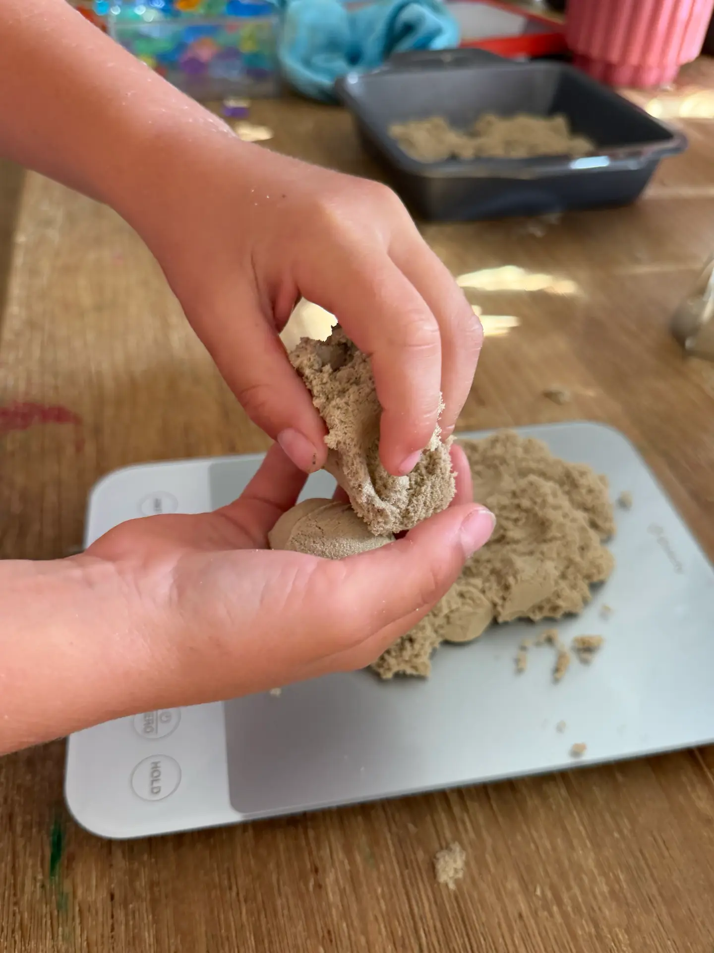 A child's hands shaping kinetic sand for a party bag project at the craft table